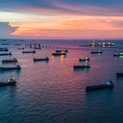 Many boats anchored in the ocean against an evening sky