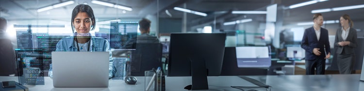 An women standing in front of a computer screen, engaged in the content displayed.