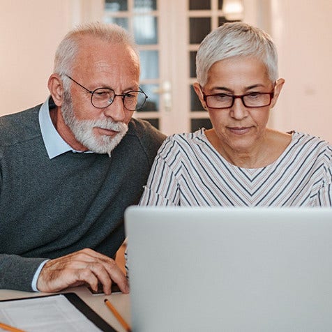 A senior couple looking at an open laptop.