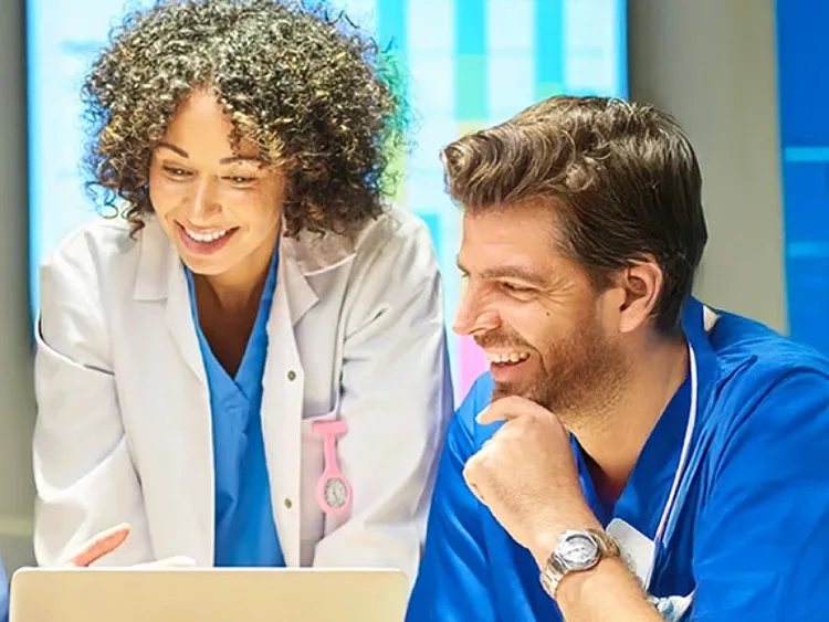 A group of doctors and nurses collaborating on a laptop in a medical setting