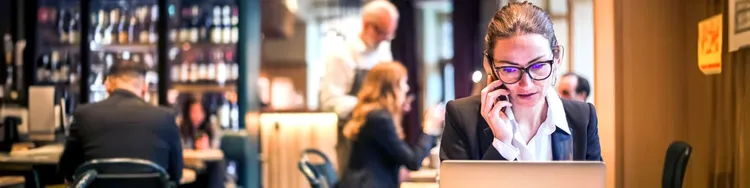 A woman talking on her mobile infront of a laptop