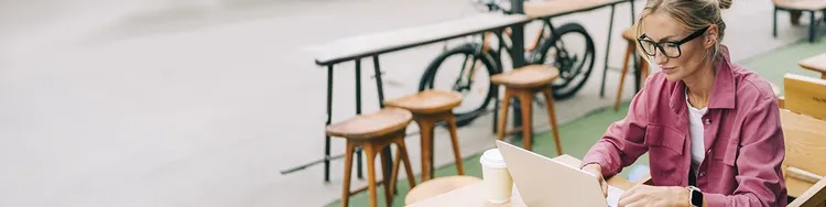 A woman seated at a table, focused on her laptop, engaged in work.