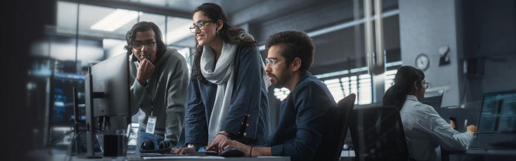 Three colleagues looking at a computer screen at work