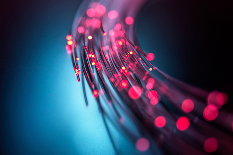 A close up of a fiber optic cable with light passing through the transparent strands.