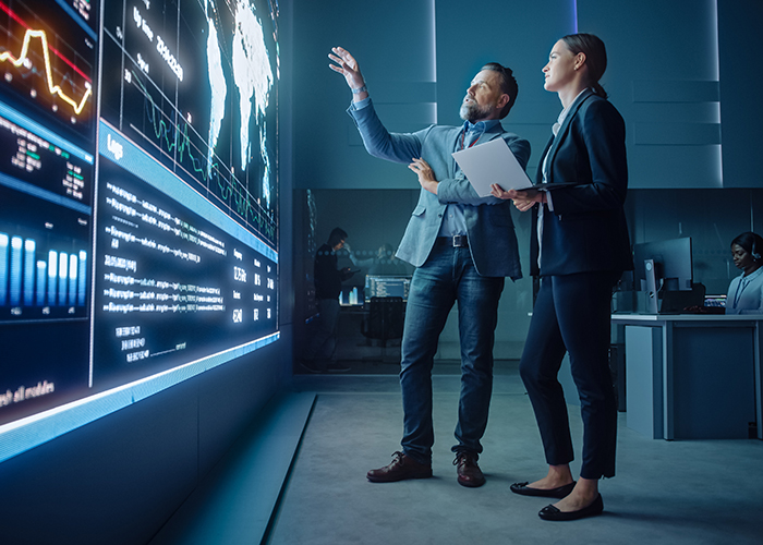 two employees analyzing something on a large screen