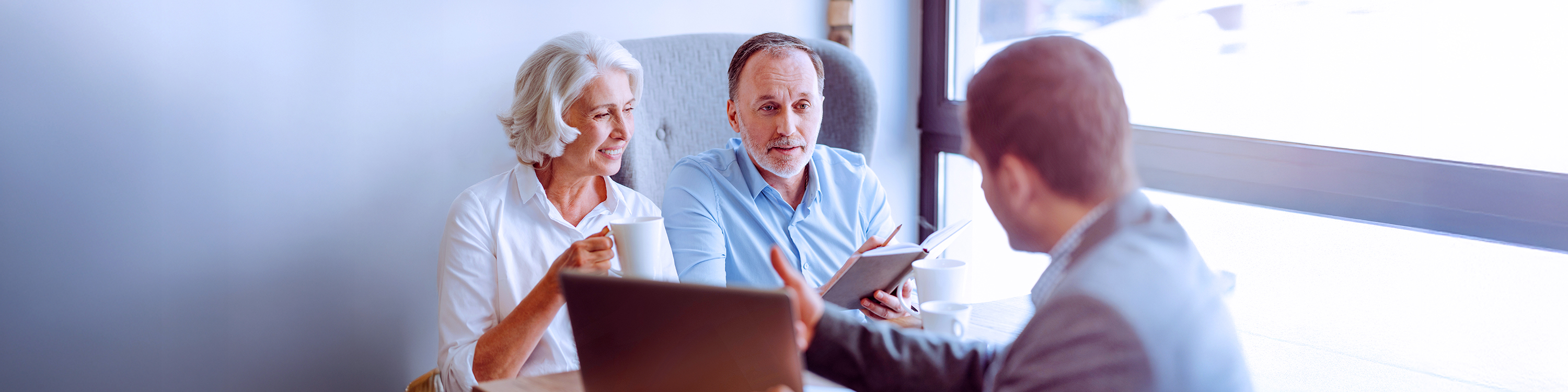 two elderly people talking with a executive looking at laptop