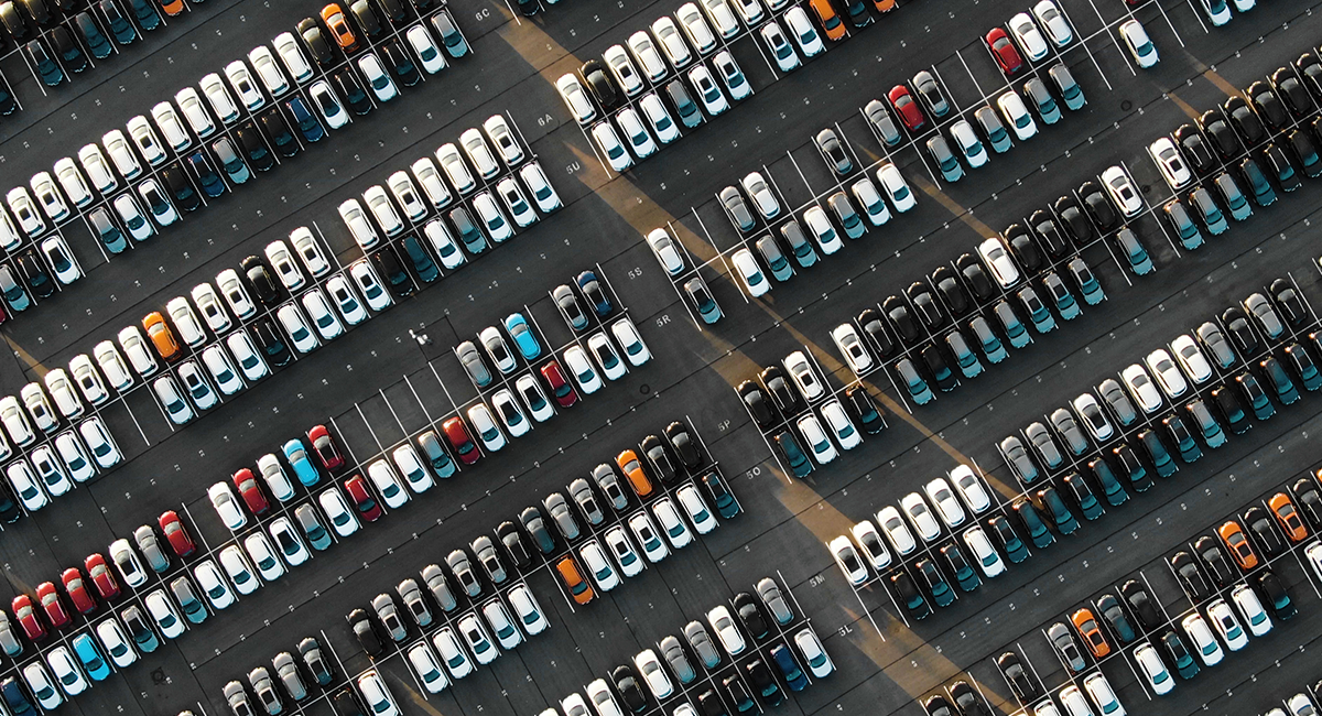 Aerial view of a crowded parking lot filled with various parked cars under clear blue skies