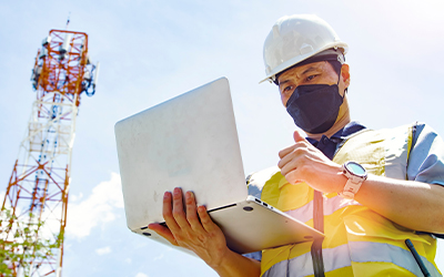 A engineer wearing mask and holding laptop in his hands