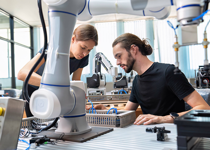 a woman working on a robot while a man looks 