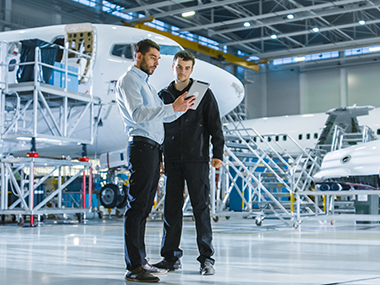 Team of Aircraft Maintenance Mechanics Looking at Airplane