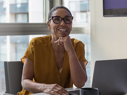 A female sitting at her desk relaxing with a smile.