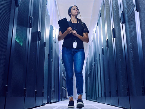 A female employee walking through a row of data center.