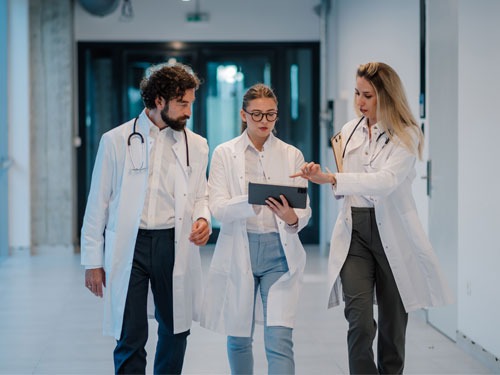 Healthcare professionals walking together while reviewing information on a tablet