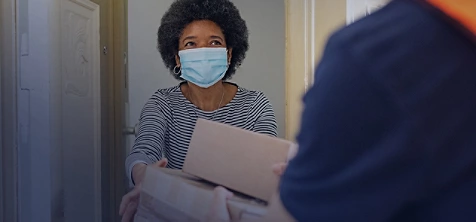 Black woman receiving parcel wearing mask
