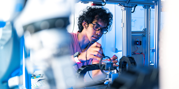 A boy assembles components on a 3d printer in a lab