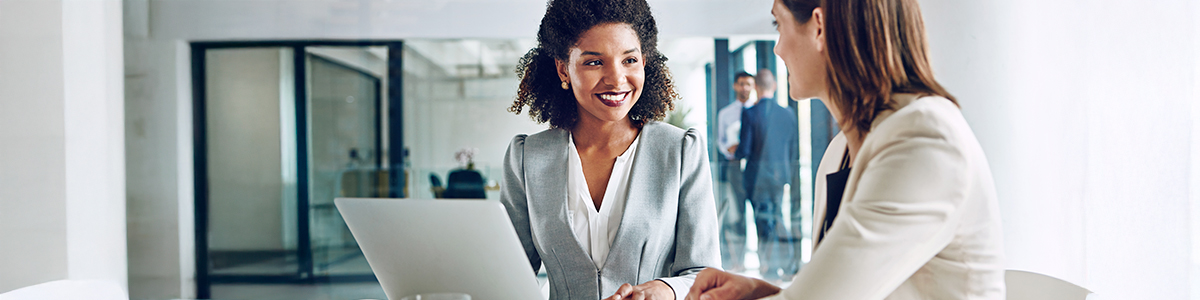 An insurance professional having a discussion with a female customer sitting on a table with a laptop open