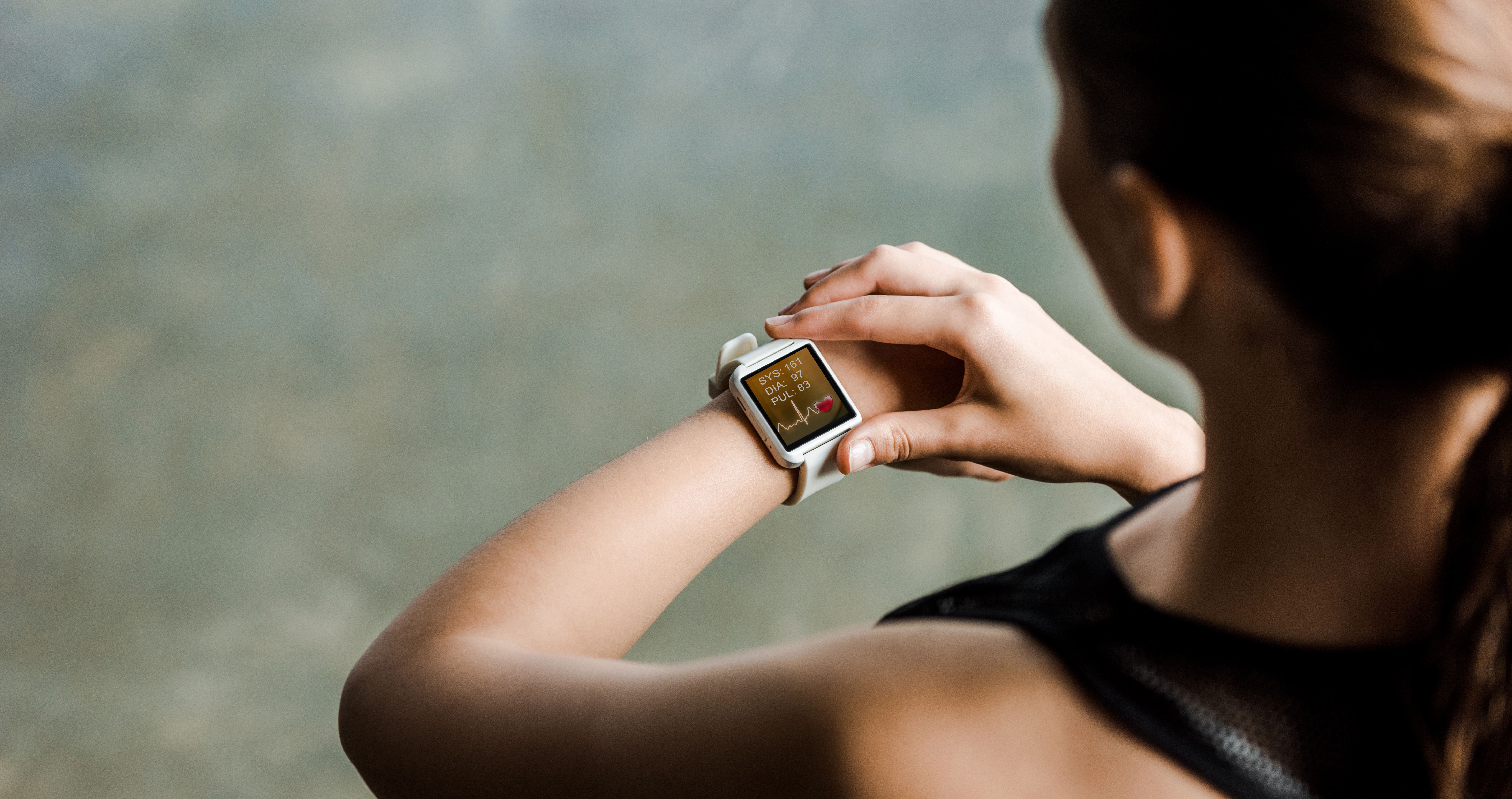 cropped view of sportswoman looking at sport smartwatch showing heartbeat rate at gym