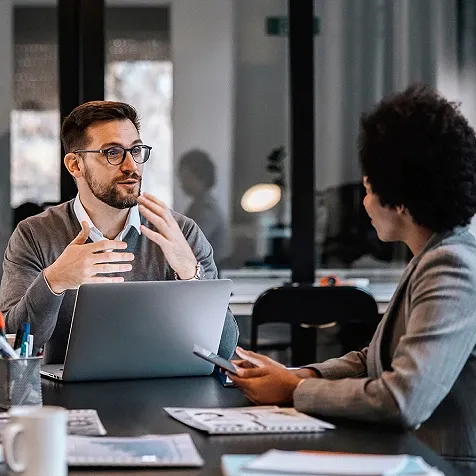 Two employees in a discussion, sitting at a desk
