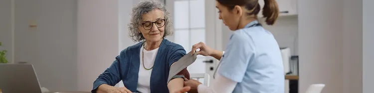 A Doctor checking with BP machine to a old lady