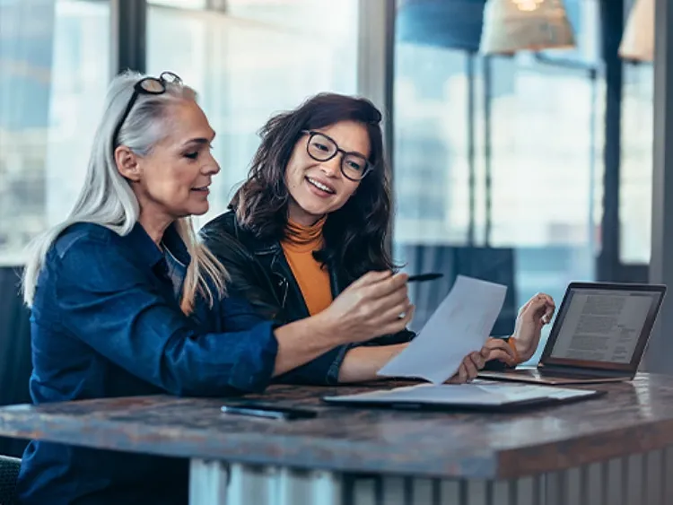 Two professional women looking at a document and talking to each other