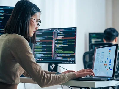 A young woman working on a laptop in an office environment