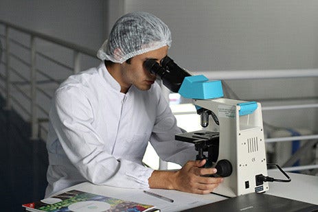 Healthcare employee looking through microscope.