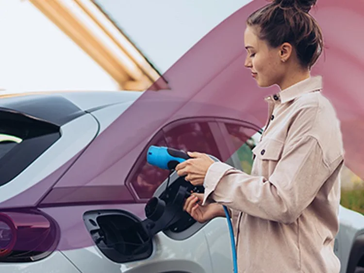 A woman connects her electric car to a charging station, preparing to recharge its battery.