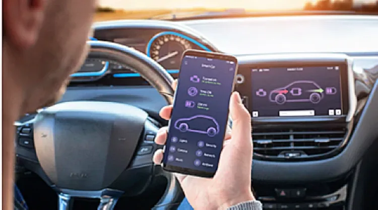 A man holding his phone will sitting on the driver seat of his car.