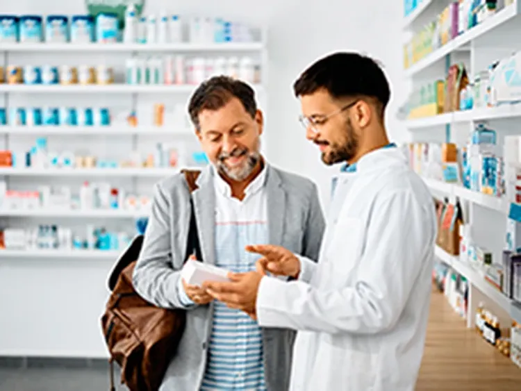 Two men standing in a pharmacy, examining a product on the shelf together