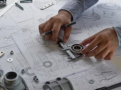 Closeup view of engineer working on blueprints, using caliper tools to measure
