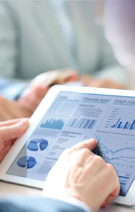 Closeup view of a tablet displaying graphs and a man's hand pointion to them