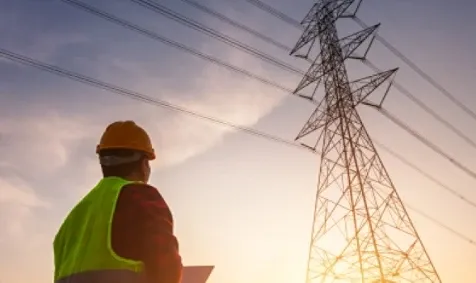 A man standing in front of an electrisd tower.