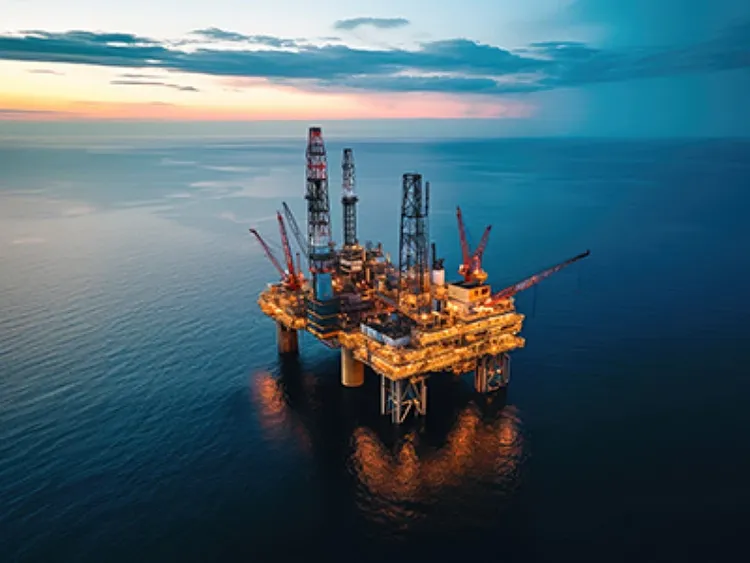 Aerial view of an offshore oil rig against a sunset sky