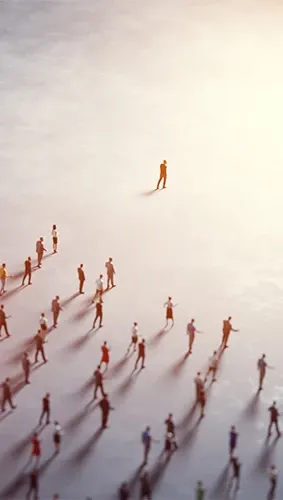 Arial view of one person walking ahead of a large group of people, towards a bright light.