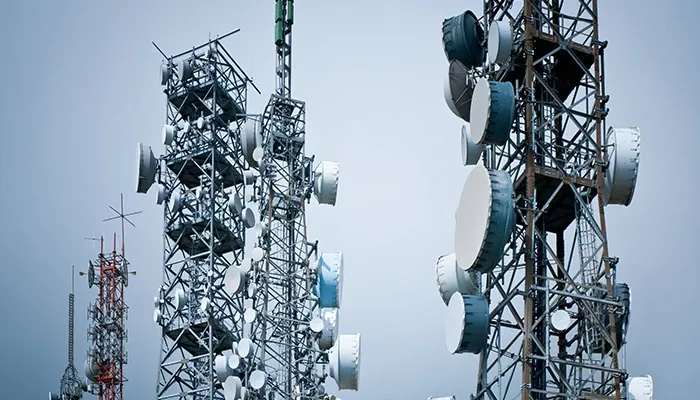 Cellular towers with multiple antennas against a clear blue sky, showcasing telecommunications infrastructure.