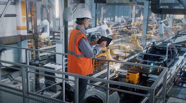 A male worker wearing safety hat and vest in factory.