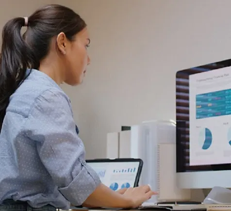 A woman sitting and working on a desktop computer.