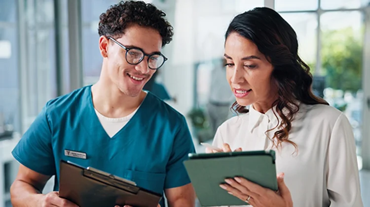 Two doctors examining a tablet computer together, discussing patient information or medical data