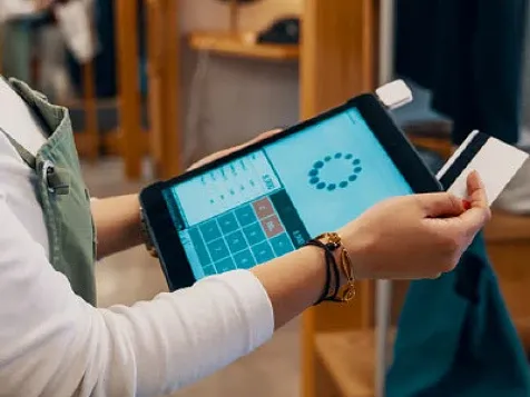 A woman holding a credit card and performing calculations on a tablet