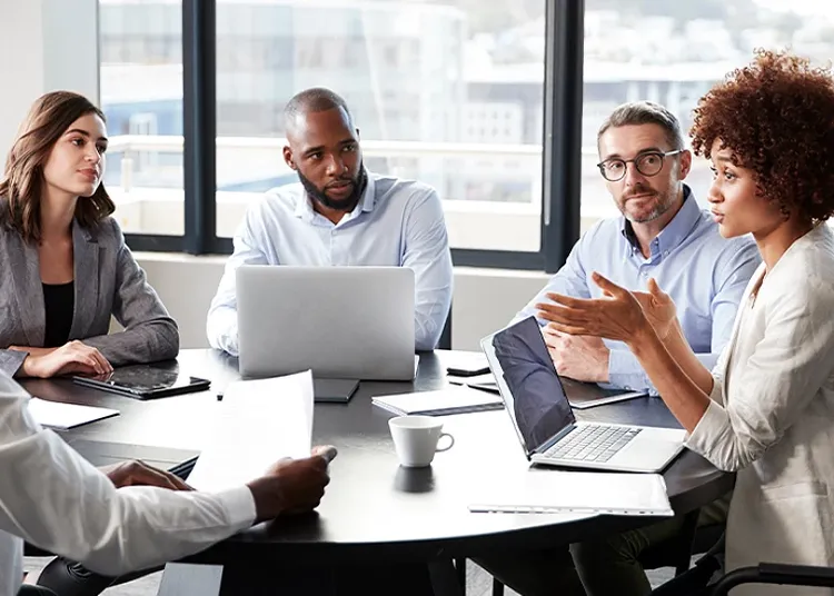 A group meeting in an office at a table with laptops open
