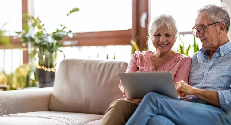 Couple sits together on a couch, using a laptop