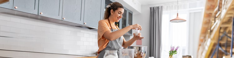 a women wearing apron holding glass in kitchen