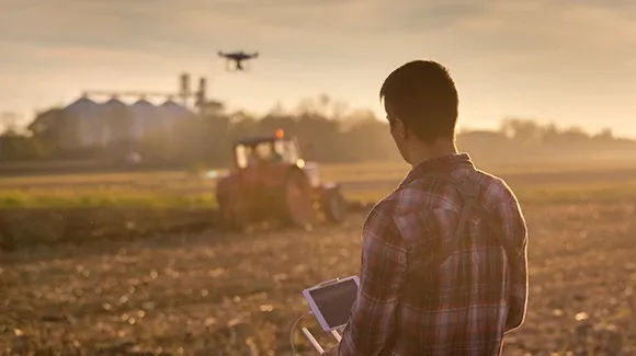 A man on his drone controller with the drone flying in the background.