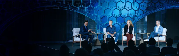 Panel discussion on stage before audience at industry event.