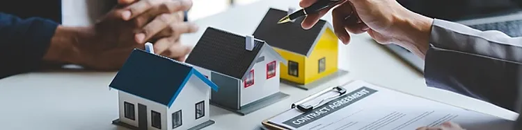 Three models pf houses lined up and a Contract Agreement document on a clipboard