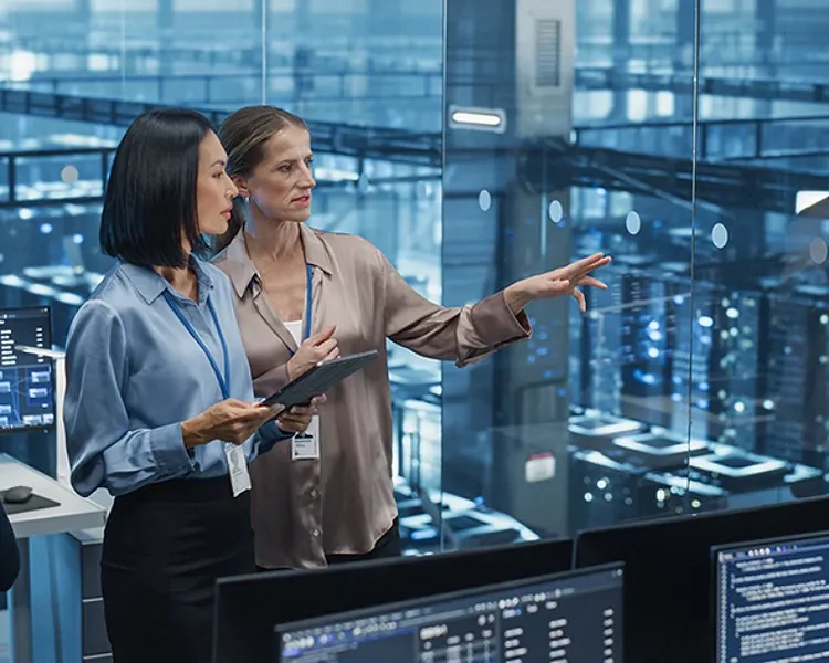 Two women discussing each other in server room.