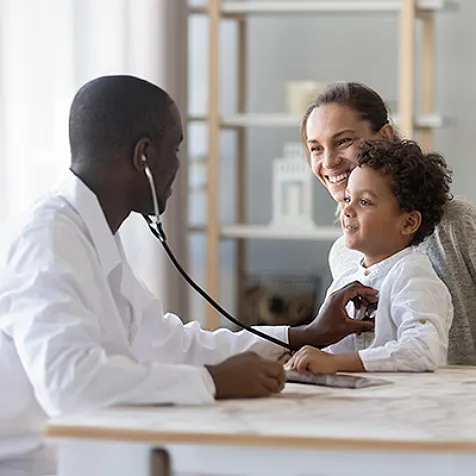 A doctor examining a young patient sitting on his mother's lap