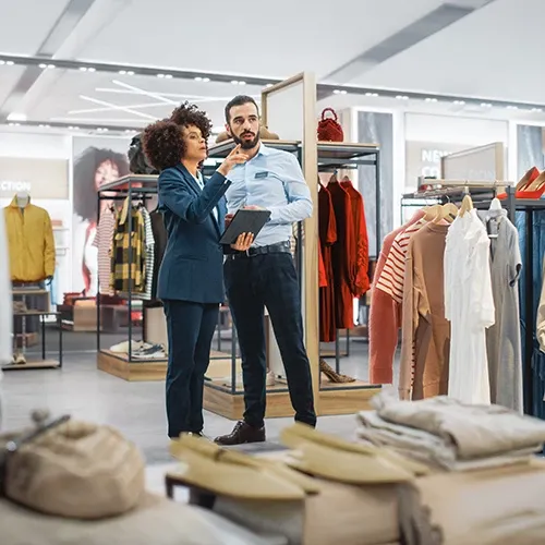 Retail associates reviewing data on a tablet in a clothing store.