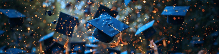 Graduation caps are tossed into the air, captured mid-flight against a blurred background of trees and warm, glowing lights.