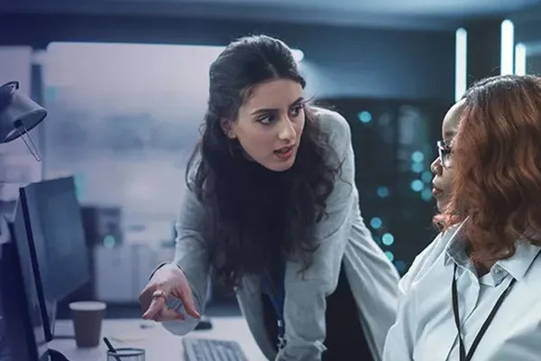 Two women collaborating in front of a computer screen, engaged in discussion and reviewing information together.